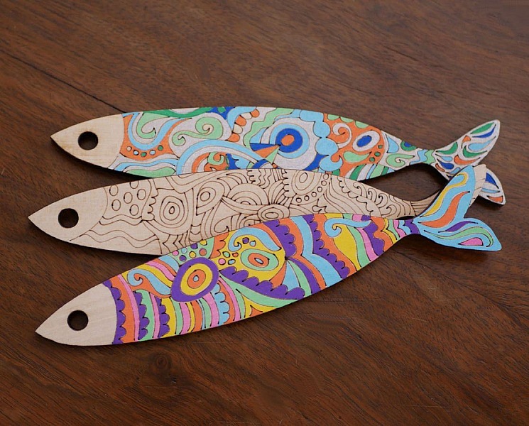 Trois poissons en bois décorés de motifs colorés artisanaux.