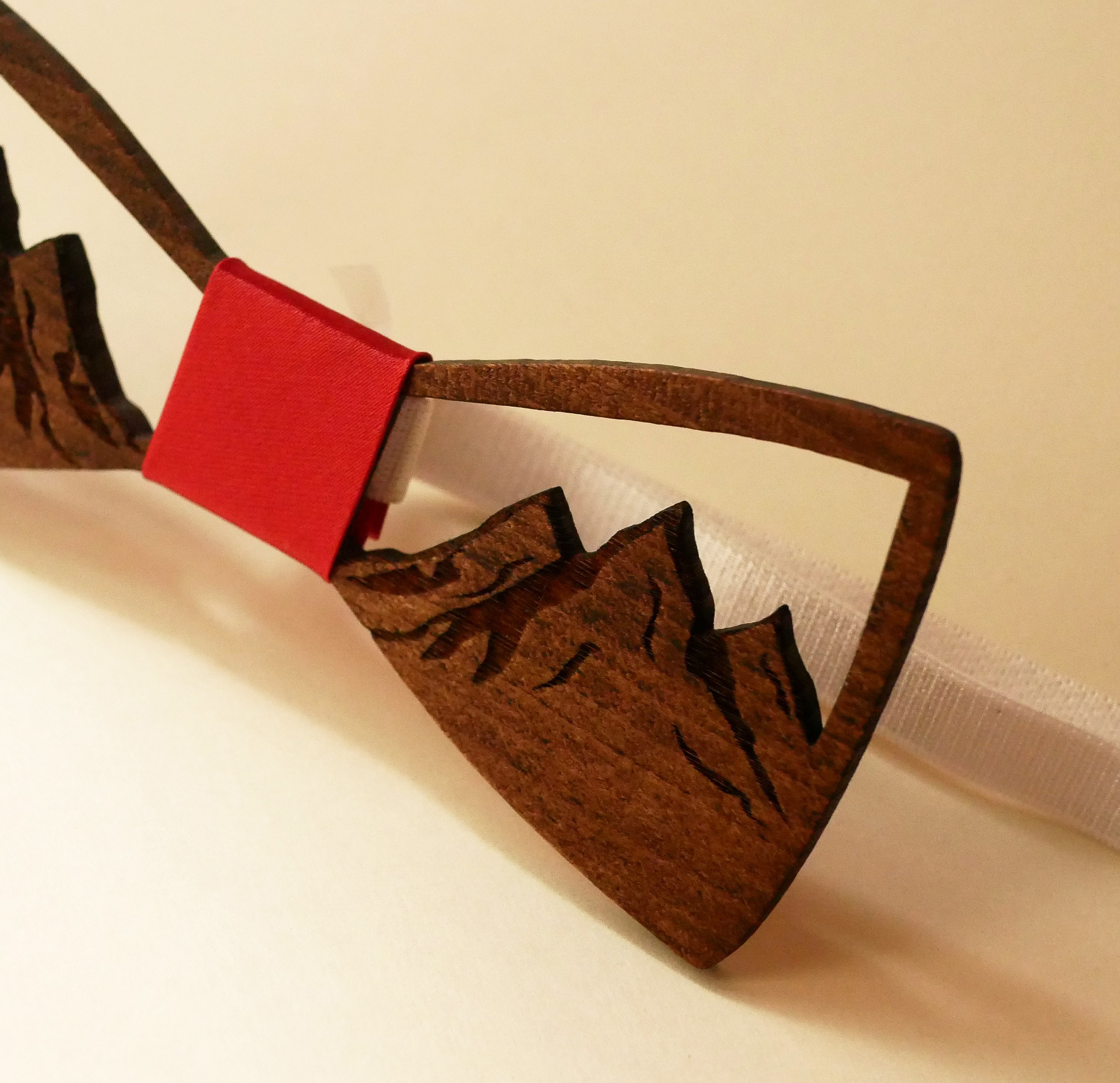 Nœud papillon en bois sculpté avec motif de montagne.