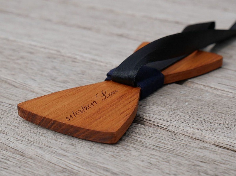 Noeud papillon en bois gravé avec ruban noir.