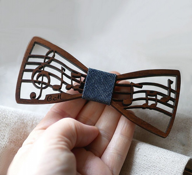 Nœud papillon en bois découpé avec motif de partition musicale.
