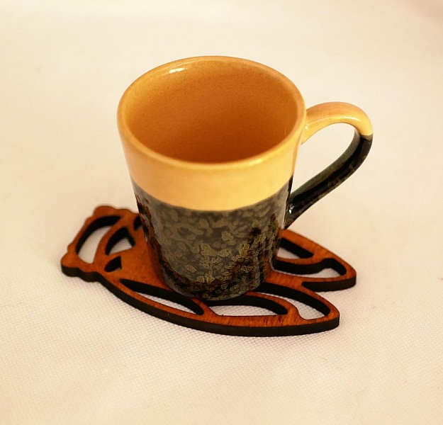 Tasse en céramique sur un dessous de verre en bois.