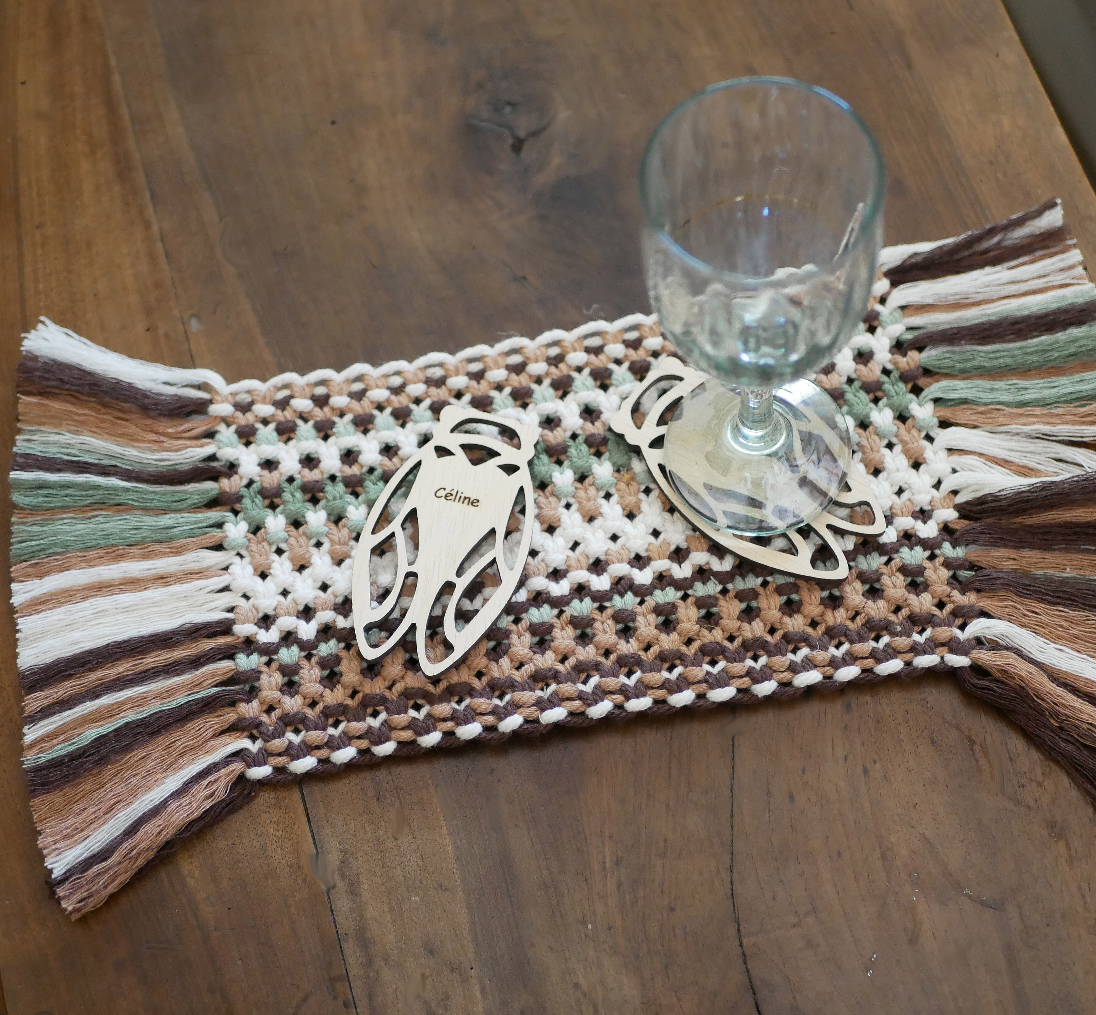 Sous-verres en bois personnalisés sur un chemin de table macramé.